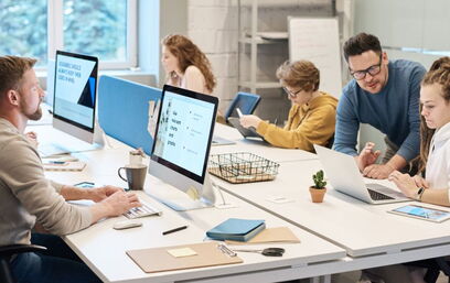 Team working on computers and tablets in a modern office