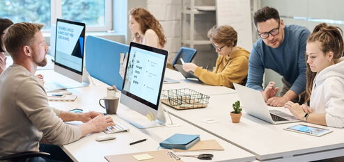 Team arbeitet an Computern und Tablets in einem modernen Büro