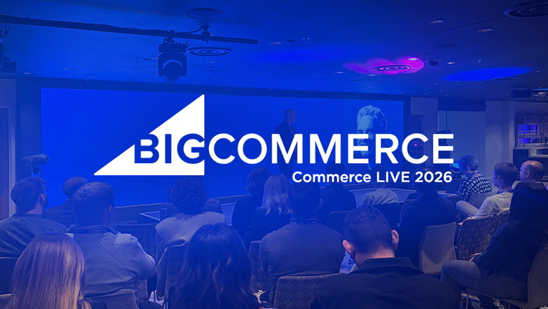 Audience seated in a conference room facing a stage with large BigCommerce logo and presentation.