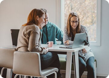 Three colleagues working together on a laptop in the office.