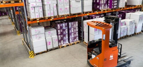 Forklift in a warehouse in front of many goods