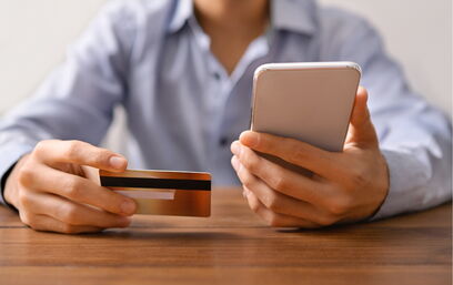Person with mobile phone and credit card in hand