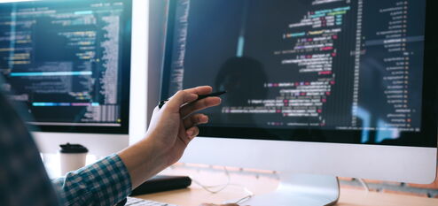 Mann deutet mit Stift auf einen Computer