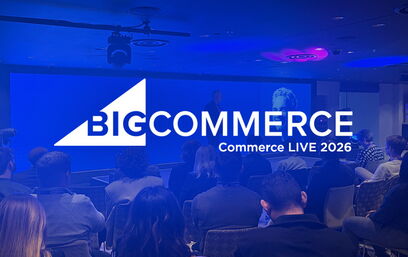 Audience seated in a conference room facing a stage with large BigCommerce logo and presentation.