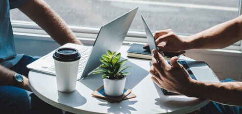 Two people sitting at a table with laptops