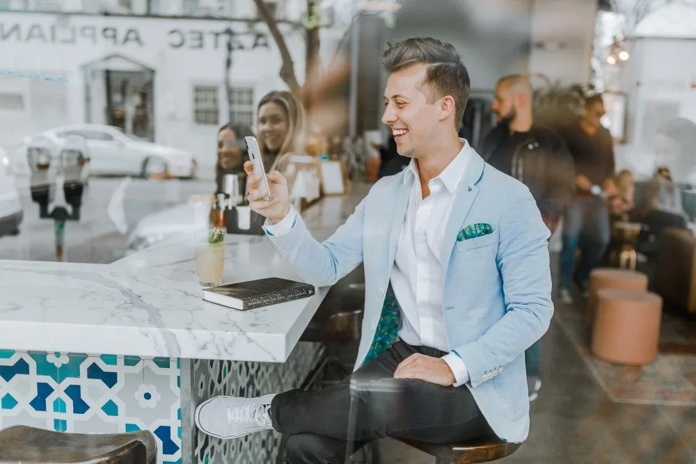 Smiling men sitting at a Bar using his Phone